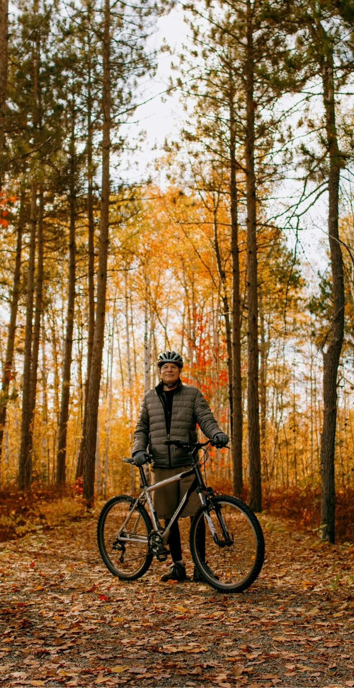 Fall scene of a man standing in the forest with his mountain bike