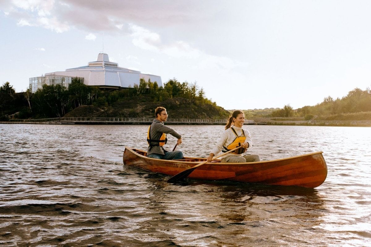 Photo of young couple canoeing on Ramsey Lake in front of Science North in Sudbury, Ontario