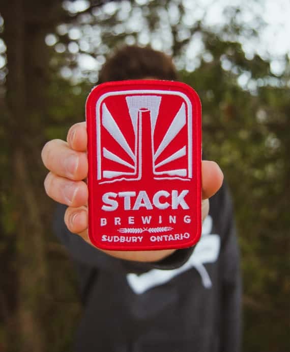 Man holding Stack Brewing patch in his hand