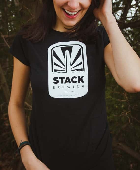 Woman wearing black Stack Brewing t-shirt with branded logo on front