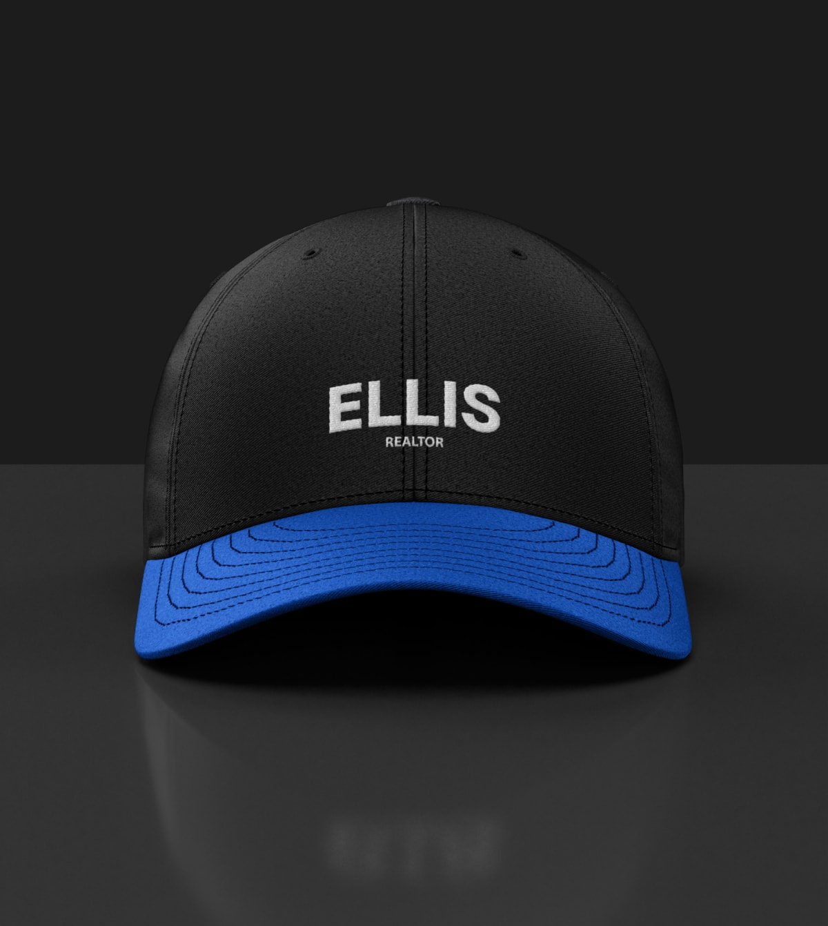 The image is a black baseball cap with a blue logo that says "ELLIS REALTOR." It can be tagged as a cap or a baseball cap.