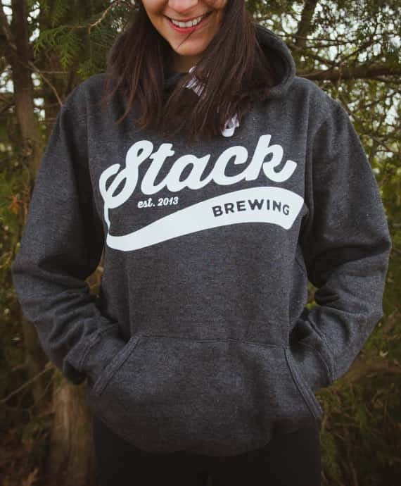 Woman wearing grey Stack Brewing hoodie with branded logo on front